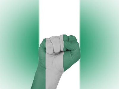 Fist wrapped in the flag of Nigeria and flag in the background